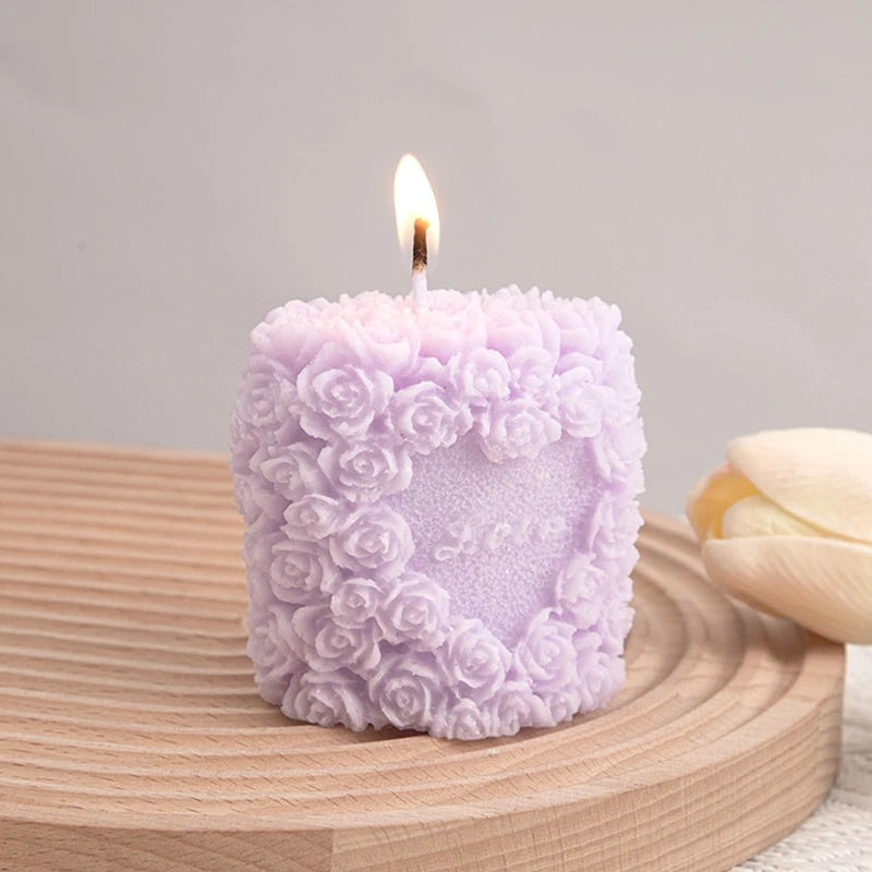Bougie Pilier Élégance Romantique, de couleur violette, posée sur une table en bois et sur fond gris.