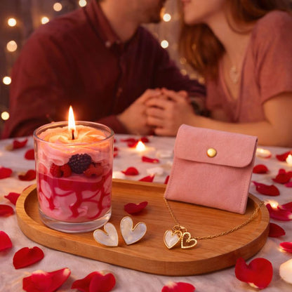 Bougie Saint Valentin Coffret Tendre Moment, il est posé sur une table avec des pétales rouges autour et il y a un couple en arrière plan. Ambiance romantique.