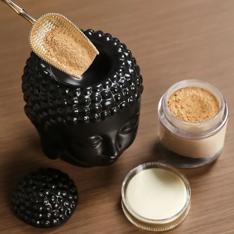 Brule Parfum Bouddha Noir Élégant, avec du fondant parfumé en poudre qu'une personne est en train de disposer à l’intérieur.