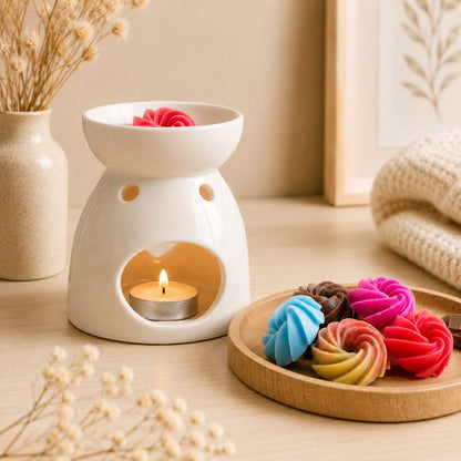 Brule Parfum Cœur Blanc en céramique avec bougie chauffe-plat allumée et fondant parfumé, accompagné de fondants parfumés colorés sur plateau en bois.