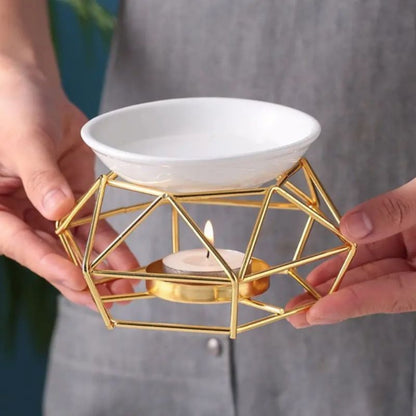 Brule Parfum Style Contemporain doré tenu dans les mains avec bougie chauffe-plat pour fondant parfumé.