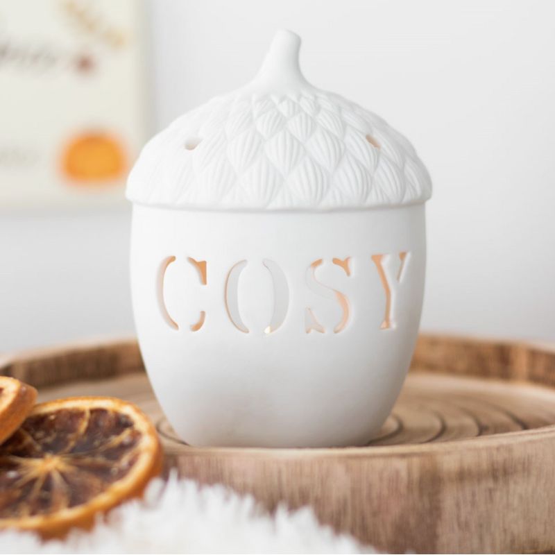 Brule Parfum Esprit Cocooning, en forme de noisette et de couleur blanc, dans une ambiance automnale.