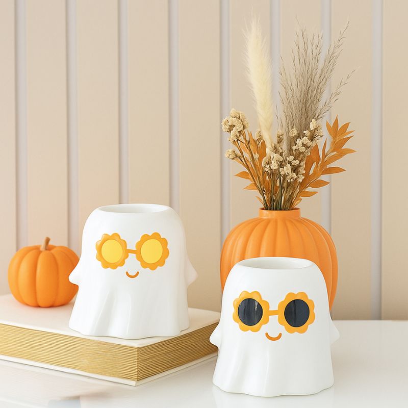 Brule Parfum Fantôme XL Stylé, dans une ambiance automnale, il y a 2 brûleurs blancs, avec un pot de fleur en forme de citrouille, le tout posé sur une table blanche.