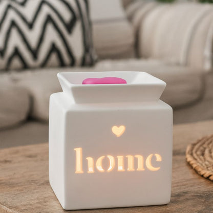 Brule Parfum Home Minimaliste, Modèle blanc ajouré « home » allumé, avec fondant parfumé en forme de cœur, diffusant une lumière douce dans un intérieur cosy.