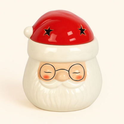 Brule Parfum Magie de Noël, de couleur blanc et rouge, en forme de tête de père Noël. Sur fond beige clair.