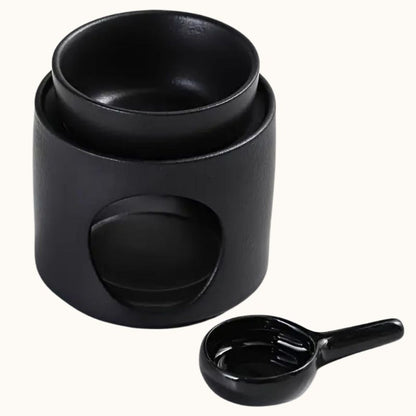 Brule Parfum Noir Design avec coupelle amovible et support pour bougie chauffe-plat pour diffuser un fondant parfumé dans la maison et sur fond beige clair.