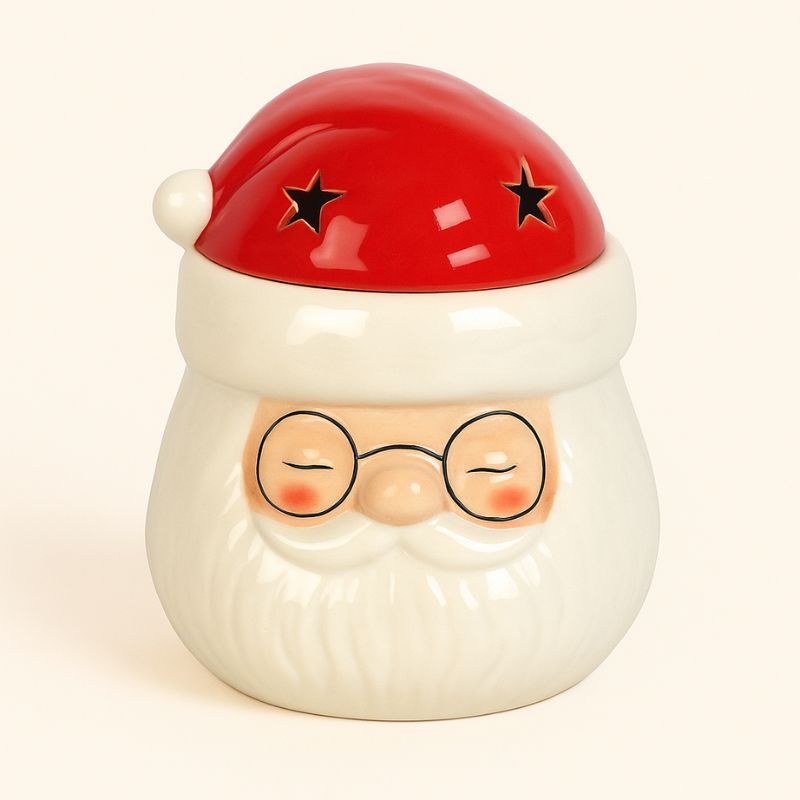 Brule Parfum Pére Noël Magique en céramique rouge et blanc avec étoiles ajourées, vue de face. Sur fond beige clair.