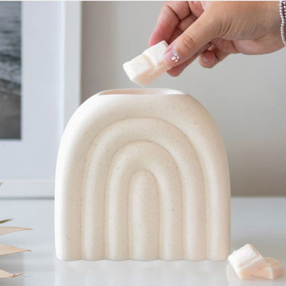 Brule Parfum XL Arc Déco Chic, une personne ajoute un fondant parfumé dans le brûleur, il est posé sur une table en marbre.