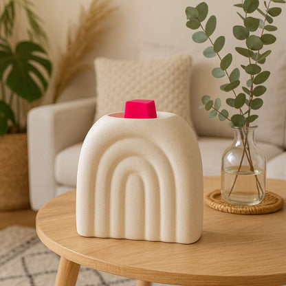 Brule Parfum XL Arc Déco Chic, posé sur une table basse avec un fondant parfumé rose, avec des plantes vertes en arrière-plan, ambiance zen.