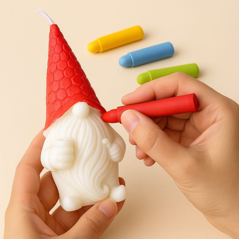 Coffret Bougie à Décorer Gnome Mystique, une personne est en train de colorier la bougie gnome blanche en rouge avec les feutres cire.