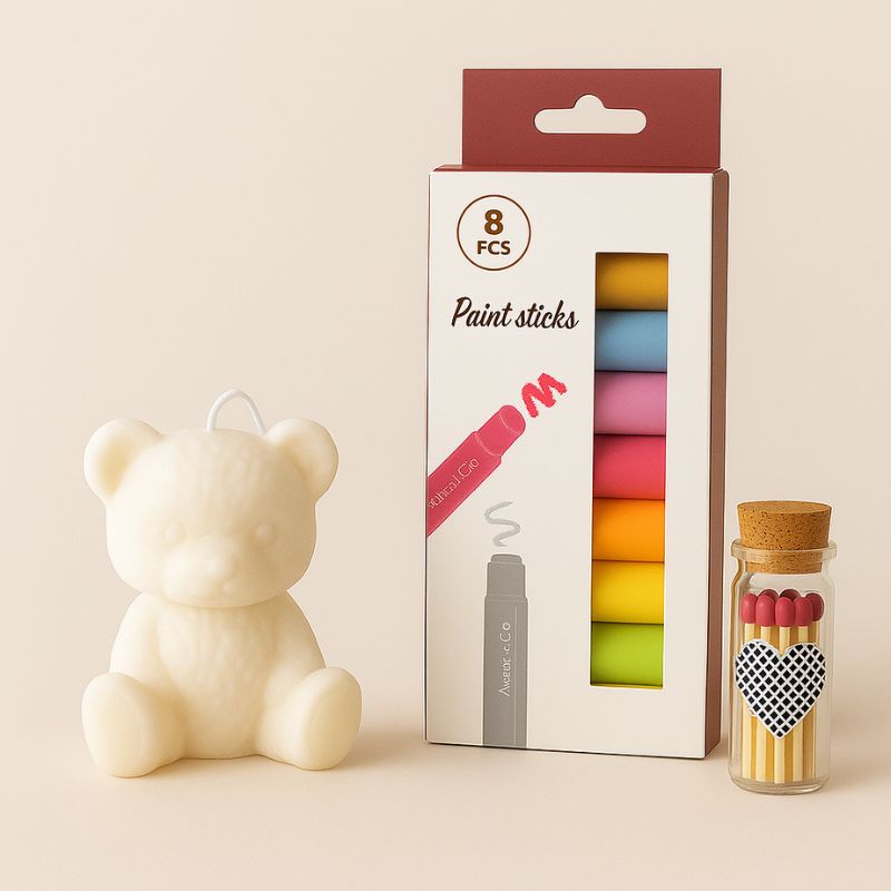 Coffret Bougie à Décorer Mission Câlin, avec tous les éléments qui le composent, bougie blanche, feutre et allumettes. Fond beige.