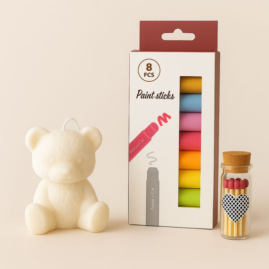 Coffret Bougie à Décorer Mission Câlin, avec tous les éléments qui le composent, bougie blanche, feutre et allumettes. Fond beige.