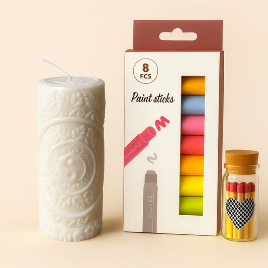 Coffret Bougie à Décorer Pilier Sculpté, la bougie est en forme de pilier blanc, la boîte de feutres cire ainsi que les allumettes et sur fond beige.