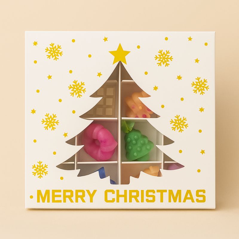 Coffret Bougie Édition Limitée Fondant Signature, boite cadeau en forme de sapin de Noël, avec des fondants parfumés à l’intérieur et sur fond beige clair.