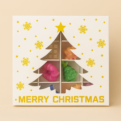 Coffret Bougie Édition Limitée Fondant Signature, boite cadeau en forme de sapin de Noël, avec des fondants parfumés à l’intérieur et sur fond beige clair.