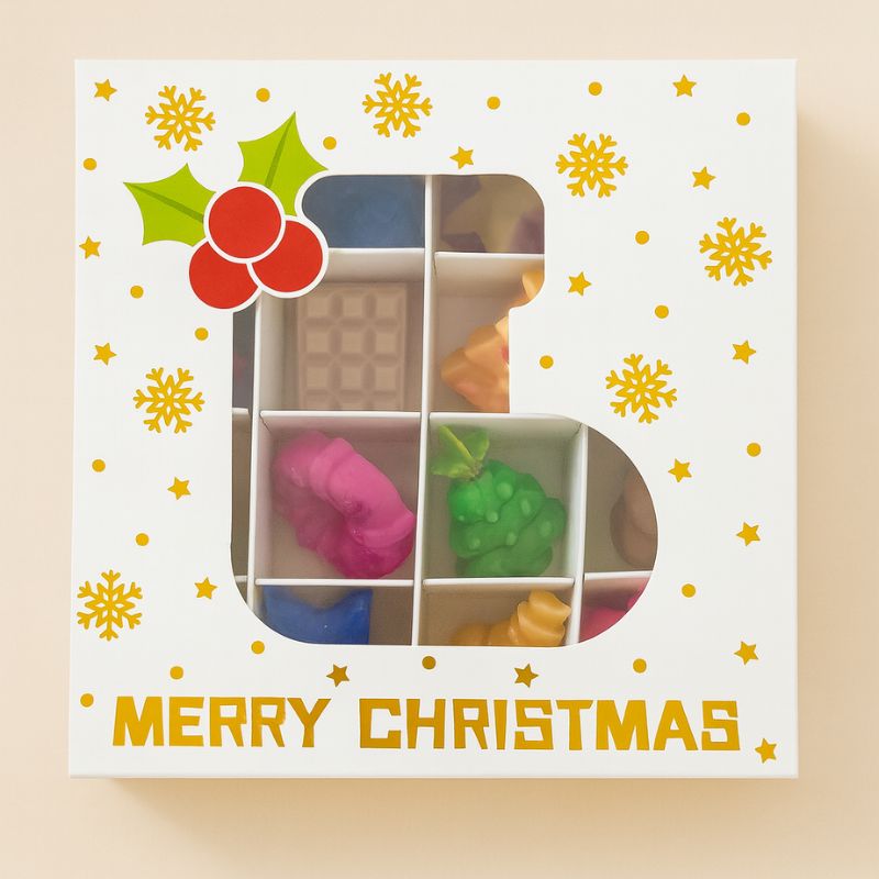 Coffret Bougie Édition Limitée Fondant Signature, la boite est en forme de botte de Noël et sur fond beige clair.