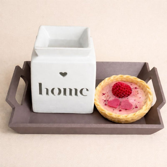 Coffret Bougie Love avec brûle-parfum Home blanc et fondant parfumé tartelette fraise sur plateau décoratif. Sur fond beige clair.