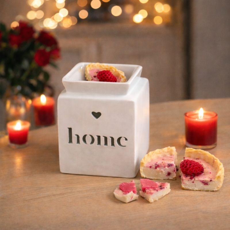 Coffret Bougie Love brûle-parfum Home blanc avec fondant parfumé tartelette fraise et bougies allumées autour, ambiance romantique.