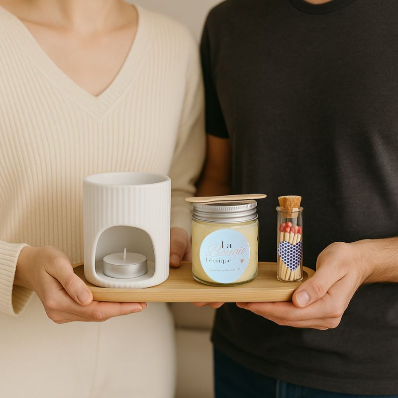 Coffret Bougie Rituel Féérique, composé d'un bruleur blanc, d'un fondant et d'un plateau en bois, que deux personnes tiennent dans leurs mains pour offrir. 