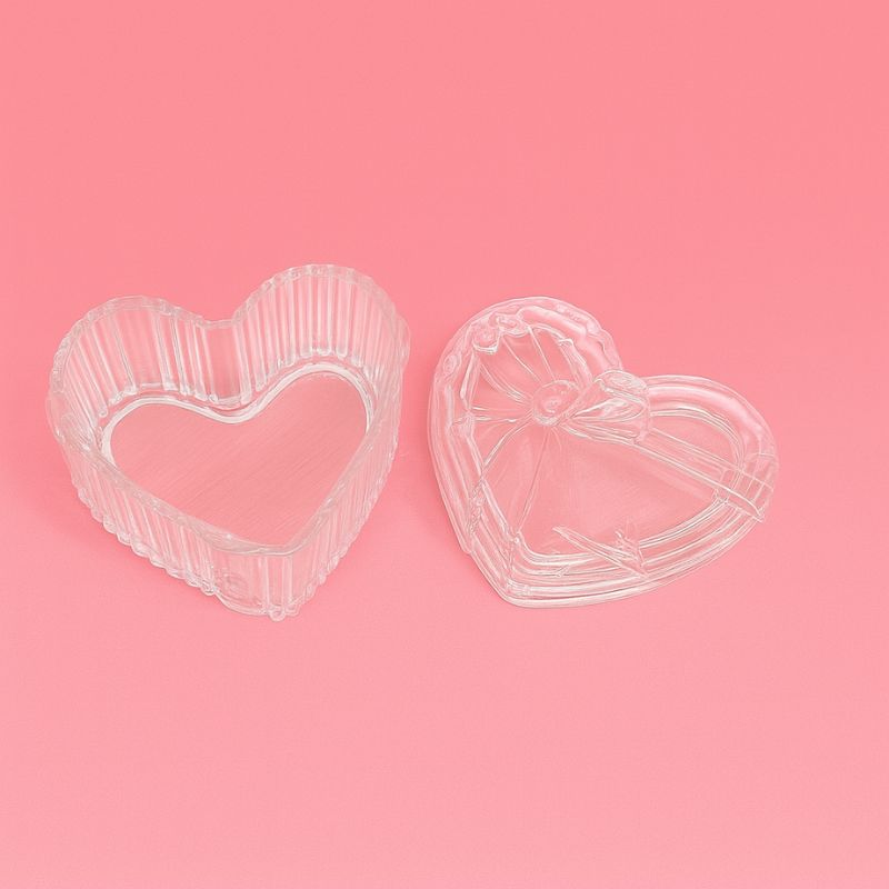 Coffret Bougies Perles Rituel Cocooning, présentation du contenant verre en forme de cœur avec son couvercle et sur fond rose.