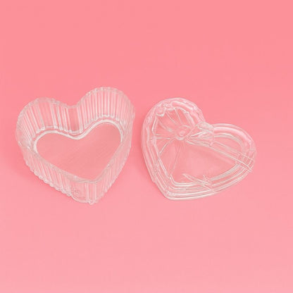 Coffret Bougies Perles Rituel Cocooning, présentation du contenant verre en forme de cœur avec son couvercle et sur fond rose.