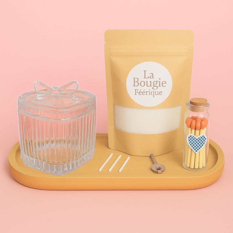 Coffret Bougies Perles Rituel Cocooning, avec un contenant en verre, un sachet de cire perles, des mèches, un plateau en bois et des allumettes, le tout sur un fond rose pâle.