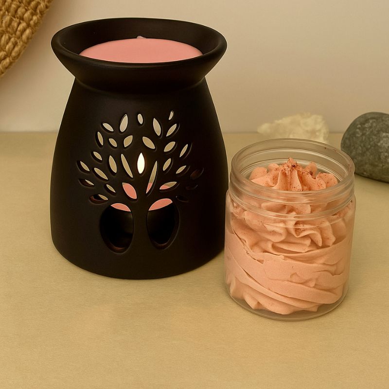 Fondant Parfumé Tentation de Fraise, dans son contenant à côté d'un brûleur noir, une petite quantité de fondant est dans celui-ci. Ambiance cocooning.