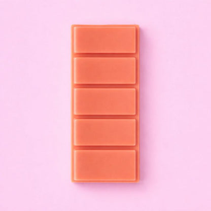 Fondant Parfumé Clémentine Monoï Snapbar, de couleur corail, format tablette sécable et sur fond rose.