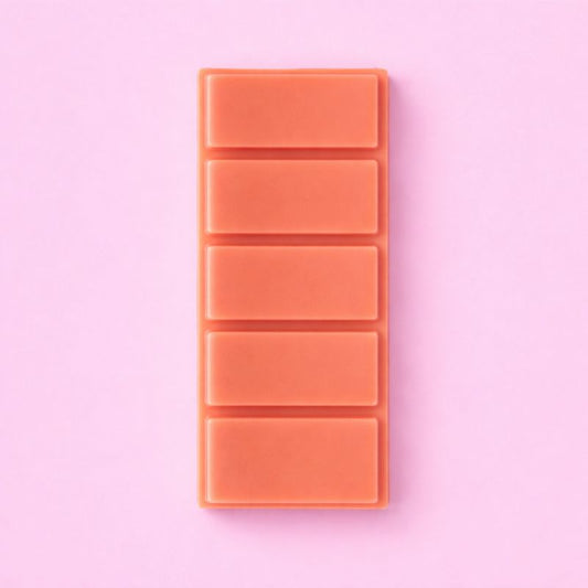 Fondant Parfumé Clémentine Monoï Snapbar, de couleur corail, format tablette sécable et sur fond rose.