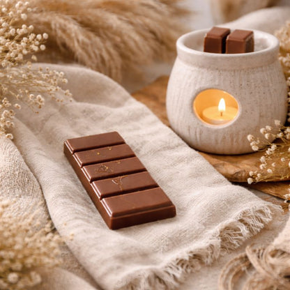 Fondant Parfumé Cola Snapbar, la barre est posée sur une étoffe en lin, il y a un brûleur a coté avec un peu de fondant à l’intérieur. Ambiance bohème.