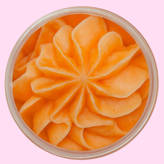 Fondant Parfumé Délice de Melon Givré, de couleur orange et la senteur melon, dans un contenant ouvert. Sur fond rose.