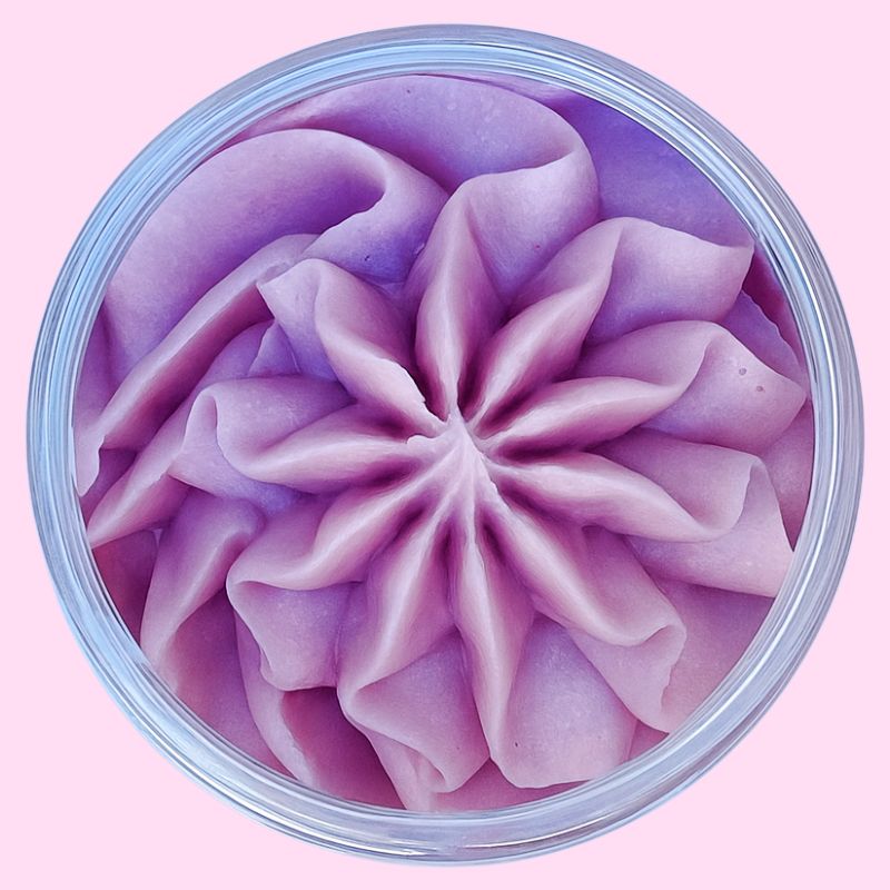 Fondant Parfumé Mûre Sauvage, de couleur violet poudré et au parfum de mure, dans son contenant en vue du dessus. Sur un fond rose.