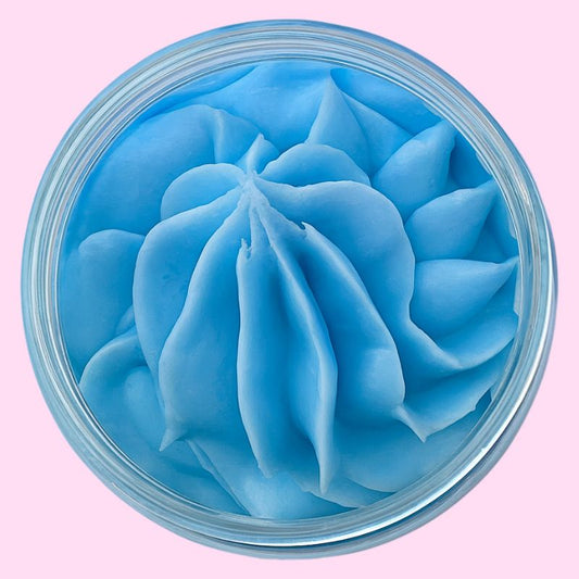 Fondant Parfumé Rêve de Coton, de couleur bleue et crémeux, dans son contenant. Sur fond rose.