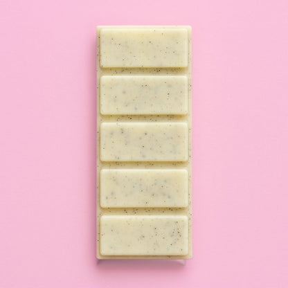 Fondant Parfumé Snapbar Bûche de Noël, de couleur jaune avec des paillettes, en forme de tablette et le parfum est bûche de Noël. Sur fond rose pâle.