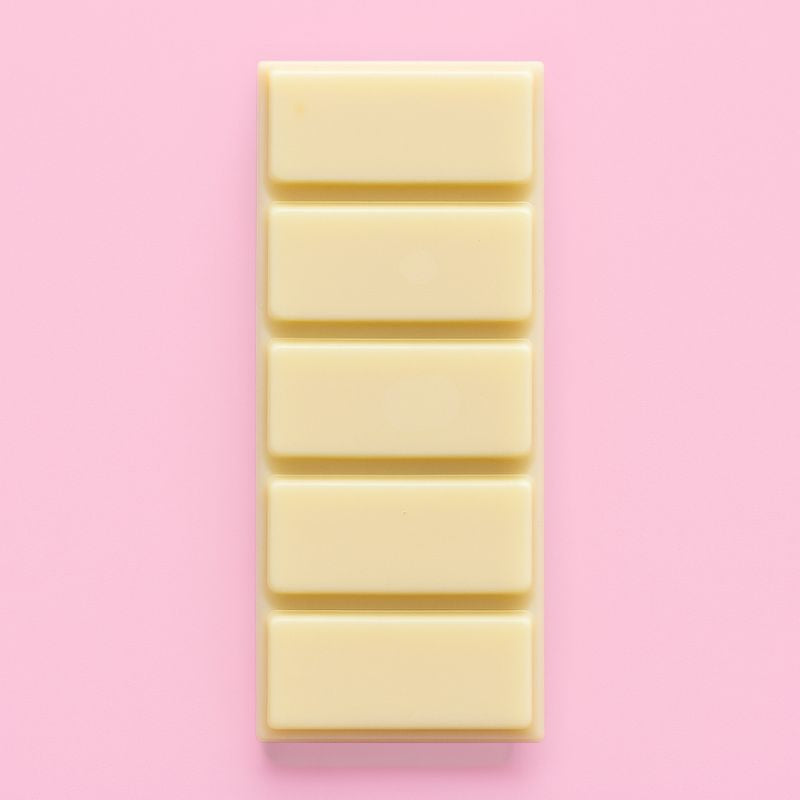 Fondant Parfumé Snapbar Nougat Blanc, de couleur jaune, en forme de tablette et parfum Nougat. Sur fond rose pâle.
