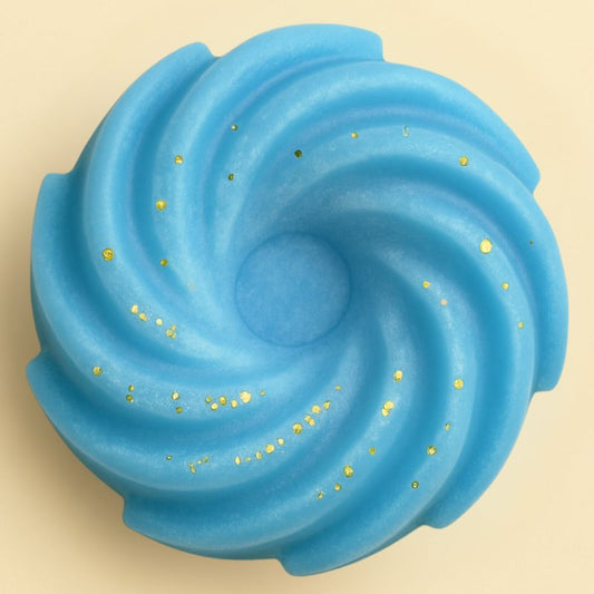Fondant Parfumé Spirale Adoucissant, de couleur bleue avec des paillettes, de forme spirale et sur fond beige clair.