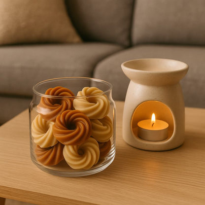 Fondant Parfumé Spirale Chocolat Cacahuète, des fondants sont dans un contenant en verre et à côté d'un brûleur et posé sur une table en bois, ambiance scandinave.