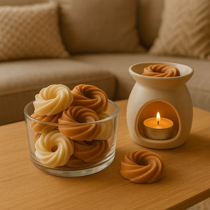 Fondant Parfumé Spirale Épicé, les fondants sont dans un contenant transparent et à côté d'un brûleur qui est posé sur une table.