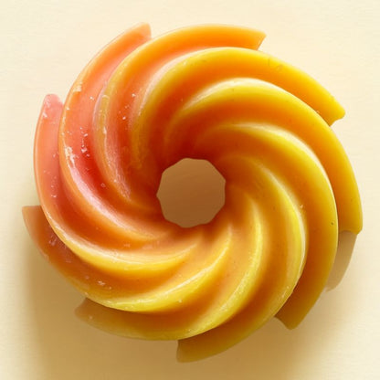 Fondant Parfumé Spirale Feu de Bois, de couleur orange, de forme spirale et sur fond beige clair.