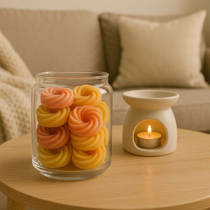 Fondant Parfumé Spirale Feu de Bois, des fondants sont disposés dans un contenant en verre, un brûleur est disposé côté, le tout posé sur une table en bois et dans une ambiance scandinave.