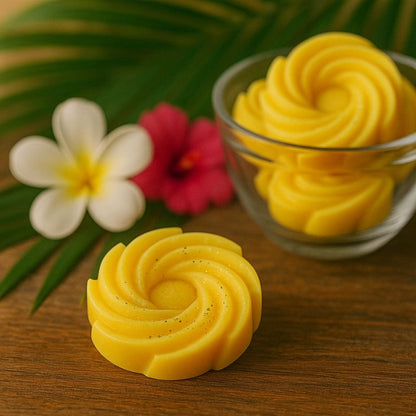 Fondant Parfumé Spirale Monoï, de couleur jaune et disposé sur une table en bois avec d'autres fondants parfumés autour.