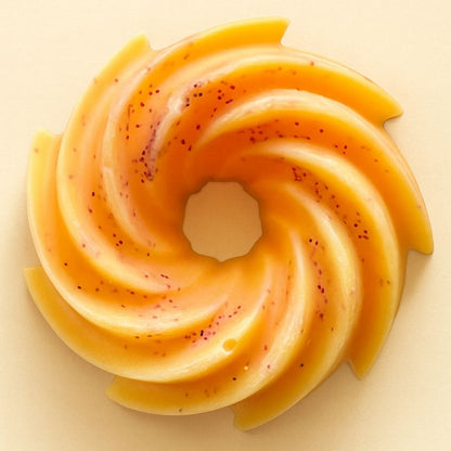 Fondant Parfumé Spirale Pacific Sunrise, de couleur orange, de forme en spirale et sur fond beige clair.