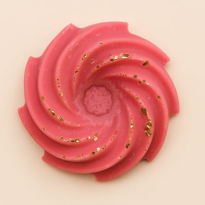 Fondant Parfumé Spirale Pomme d'Amour, de couleur rose avec des paillettes, en forme de spirale et sur fond blanc.