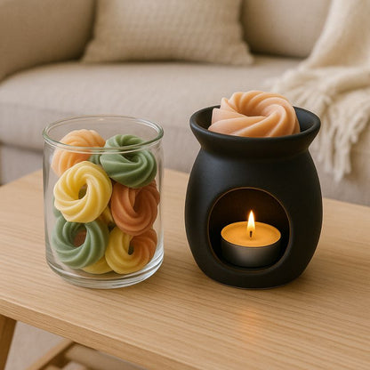 Fondant Parfumé Spirale Pop Corn, le brûleur est posé sur une table en bois et avec un fondant parfumé à l’intérieur. d'autres fondants parfumés sont disposés dans un contenant en verre. Ambiance scandinave.