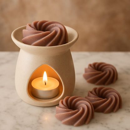 Fondant Parfumé Spirale Praliné Chocolat, il y a un fondant dans la coupelle du brûleur parfumé qui est allumé, il y a d'autres fondants posés sur la table en marbre.
