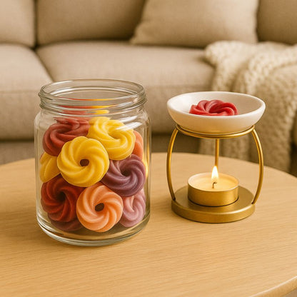 Fondant Parfumé Spirale Thé Chaï Latte, disposé dans un brûle parfum allumé, dans un contenant il y a des fondants parfumés, le tout posé sur une table basse.