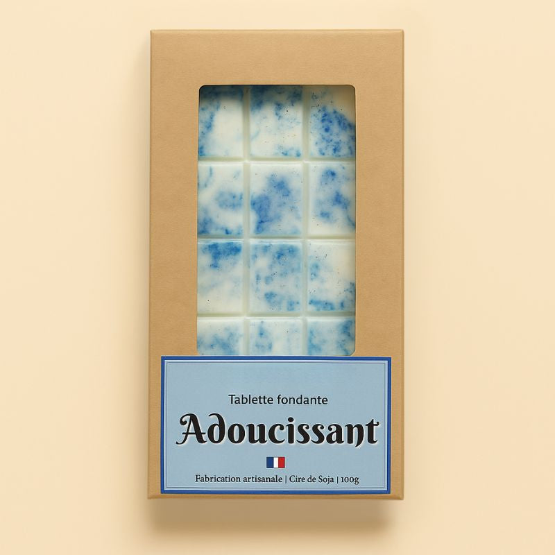 Fondant Parfumé Tablette Adoucissant, de couleur bleue et le parfum est adoucissant, dans sa boîte de conservation. Sur fond beige clair.