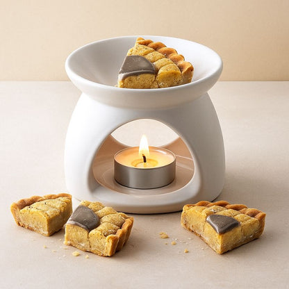 Fondant Parfumé Tartelette Châtaigne Grillé, un morceau de fondant tartelette est disposé dans le brûleur blanc et posé sur une table.