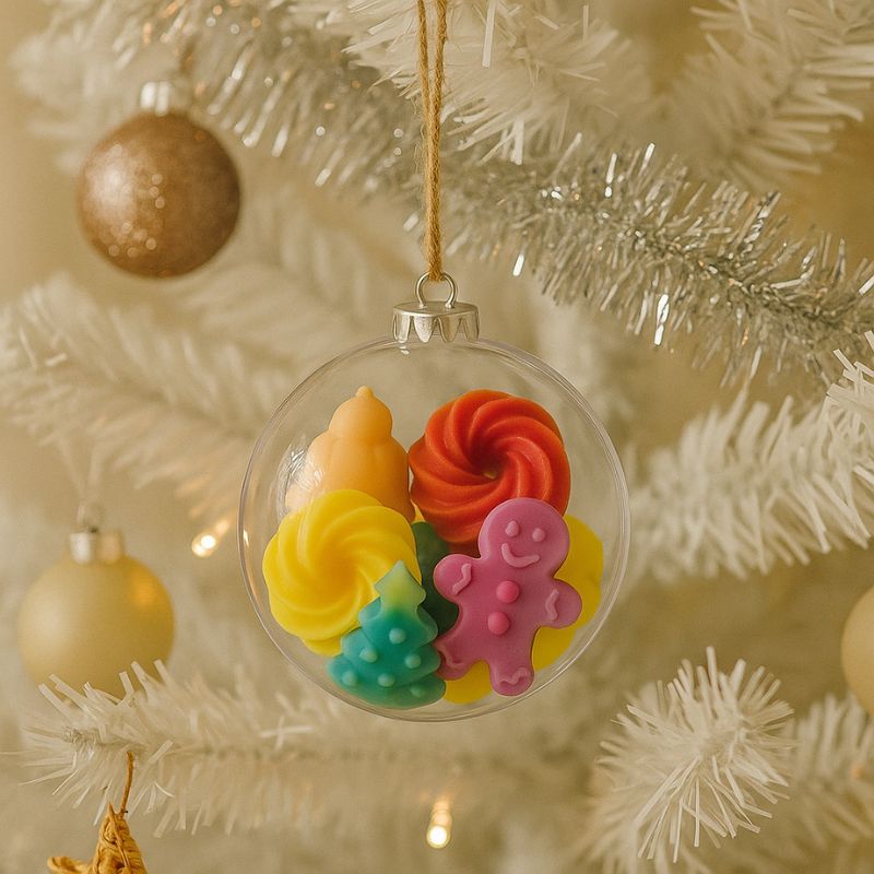 Idée Cadeau Boule Parfumée de Noël, la boule est accrochée dans un sapin blanc, il y a des fondants parfumés à l’intérieur de la boule.