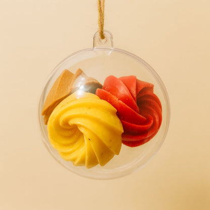 Idée Cadeau Boule Parfumée à Suspendre, 4 fondants parfumés sont à l’intérieur de la boule transparente. Sur fond beige.